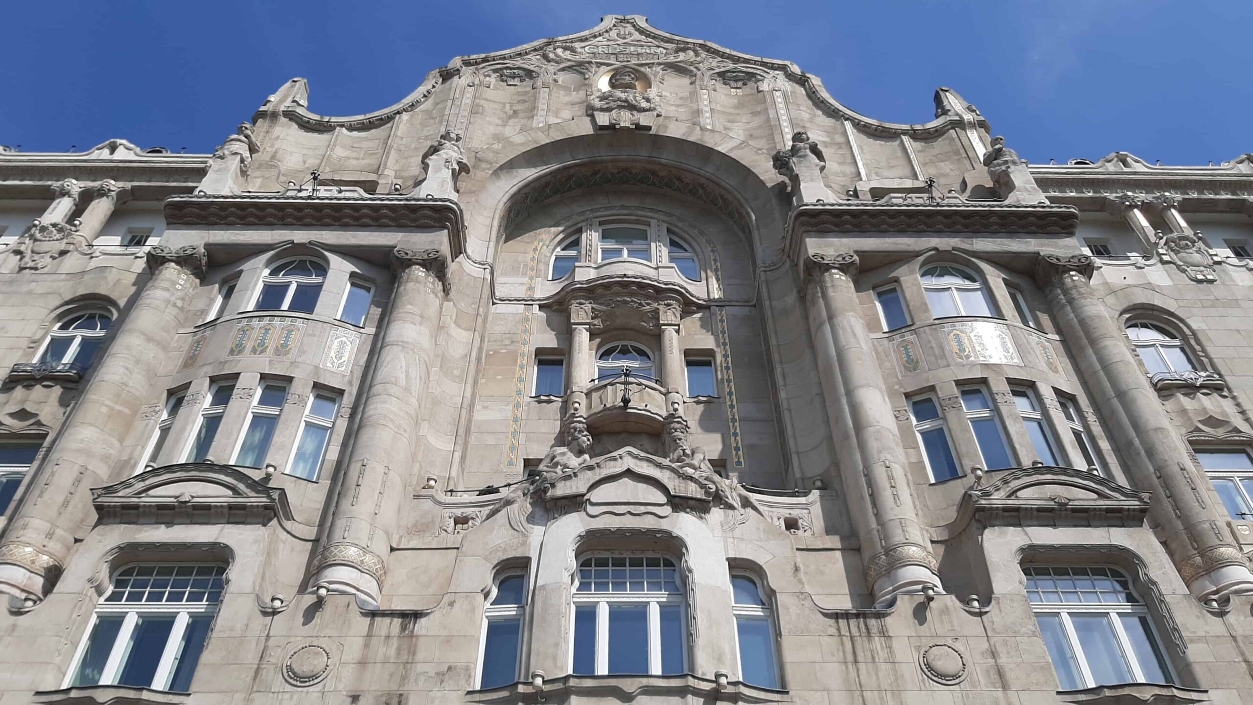 The perfectly symmetrical, illuminated Art Nouveau exterior of the Gresham Palace at dusk