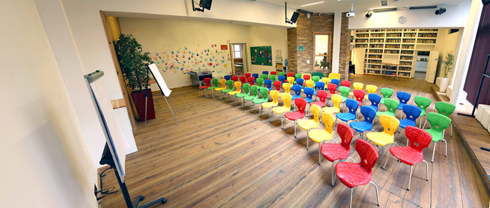 A bright, industrial event room with desks set up for a presentation inside Grund