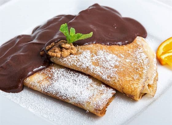 A beautifully folded Hungarian crepe generously covered in thick, dark chocolate sauce