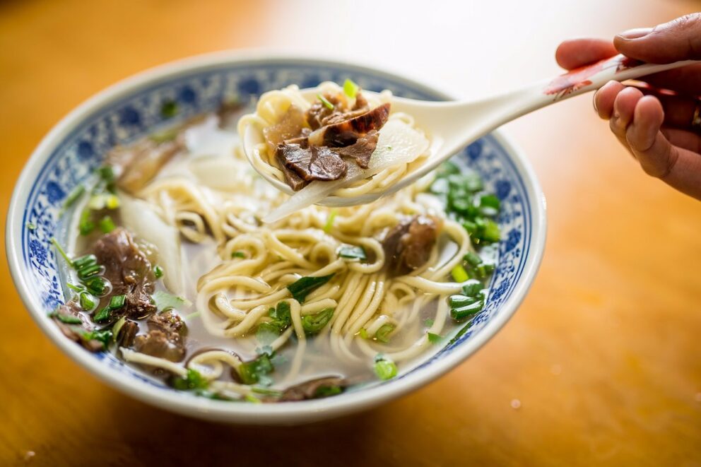 A chef's hands stretching fresh dough to make traditional lamian noodles