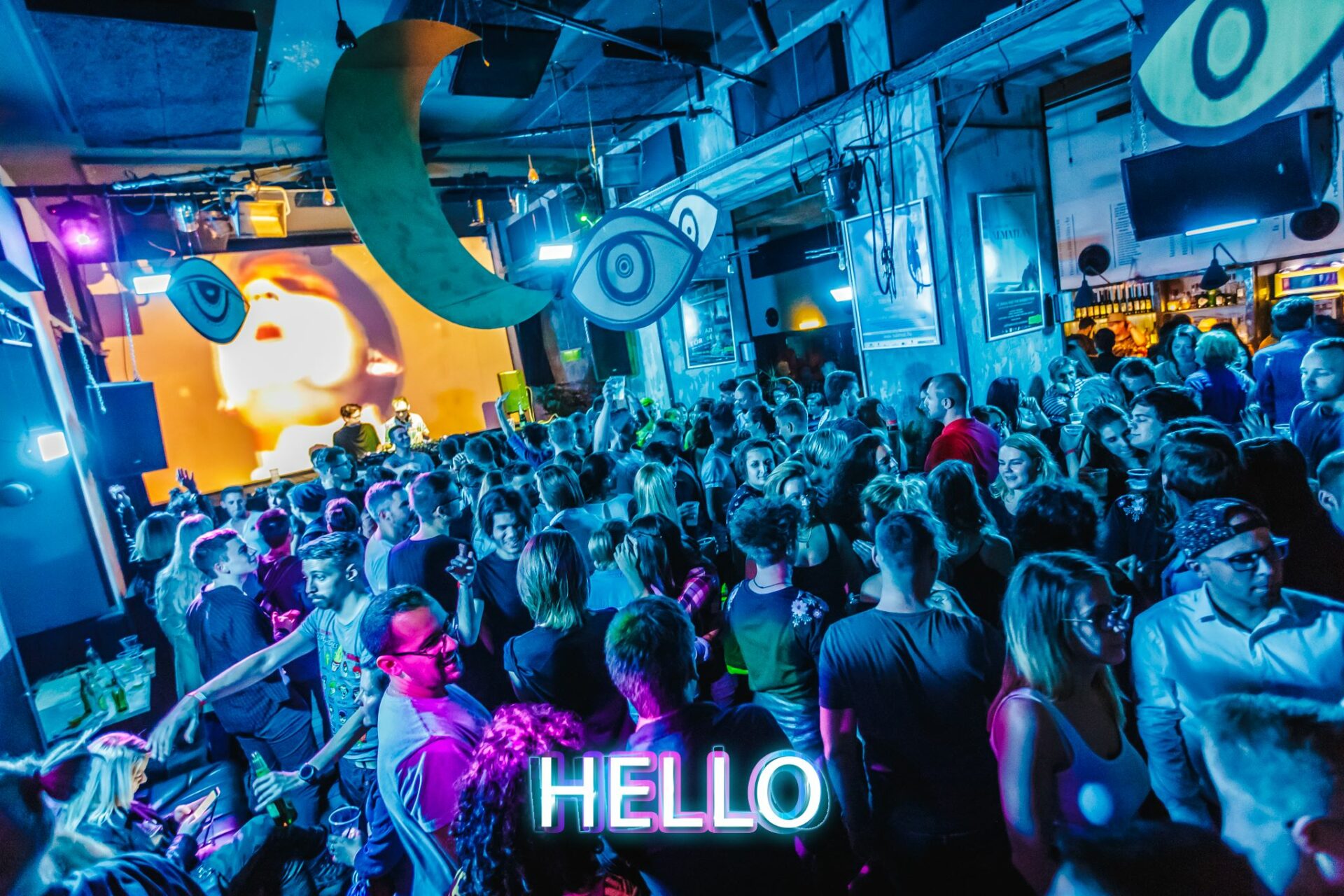 A pink neon sign spelling the word 'hello' on a dark brick wall