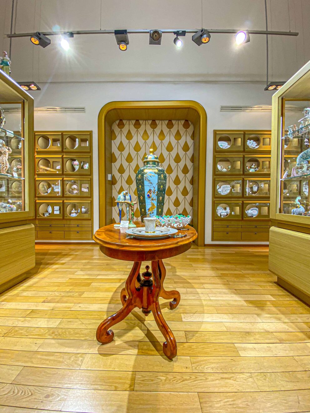 Pristine glass retail display cases filled with various Herend porcelain sets inside a Budapest store