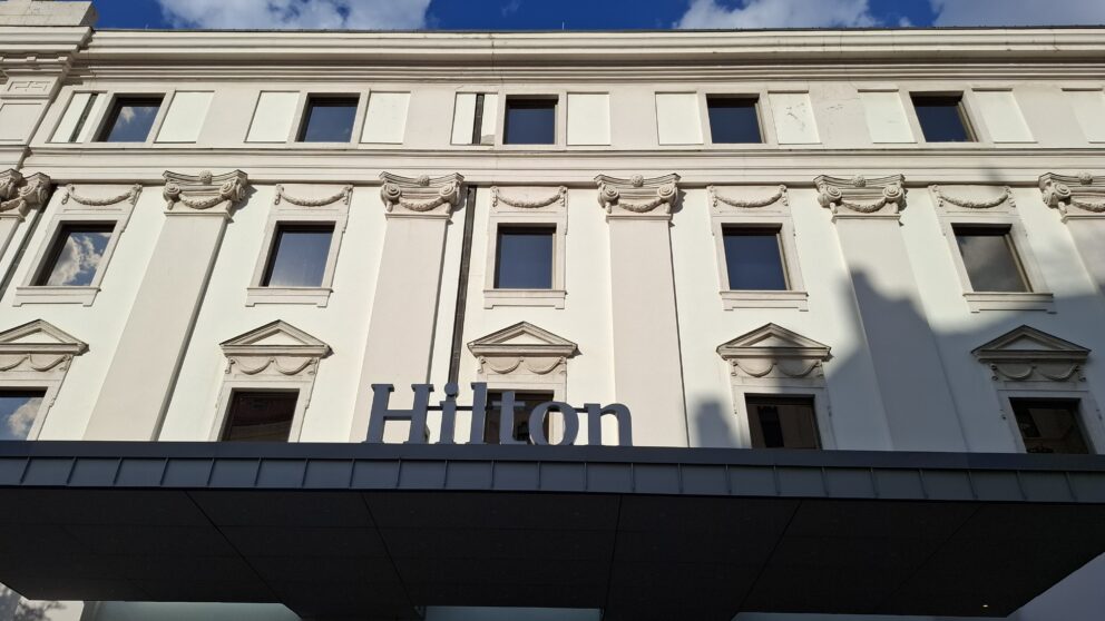 The modern glass facade of the Hilton Budapest towering directly behind Fisherman's Bastion