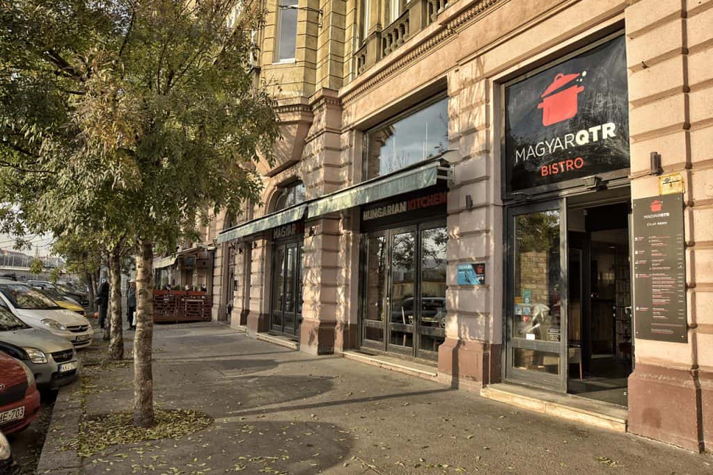 Soft dough being pushed through a traditional nokedli maker into boiling water