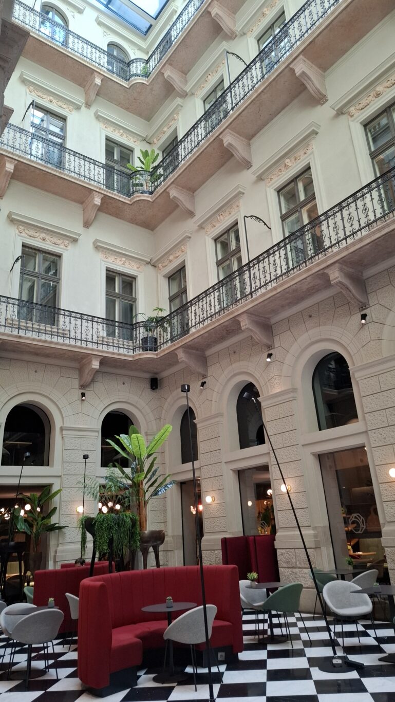 An incredibly detailed inner courtyard covered by a modern glass roof featuring ornate black wrought-iron railings