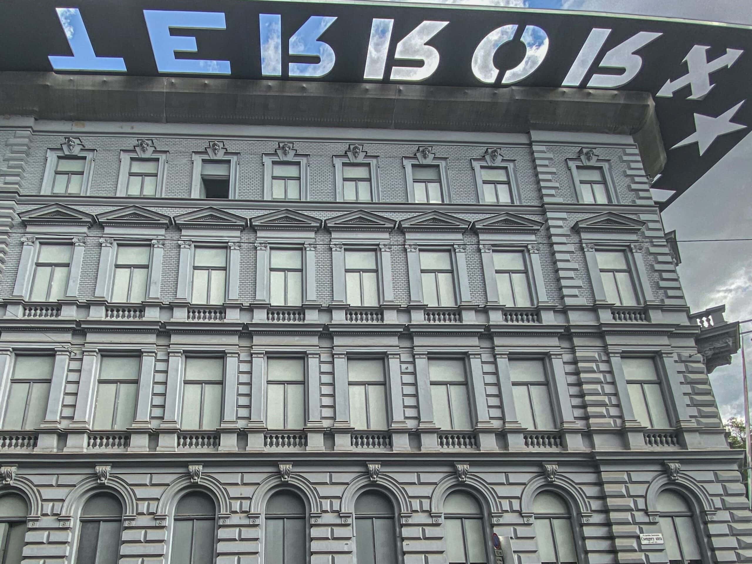 The grey facade of the House of Terror Museum in Budapest with the 'TERROR' cutout roof