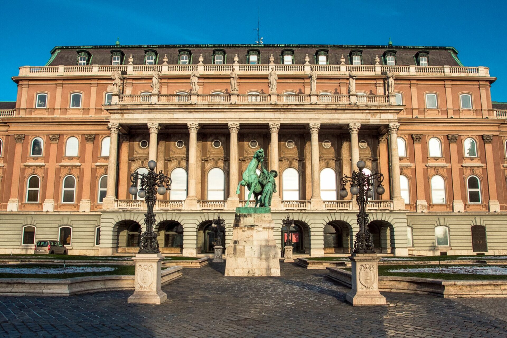 The massive royal palace housing the Hungarian National Gallery featuring grand stone columns and the bronze Horse Tamer statue
