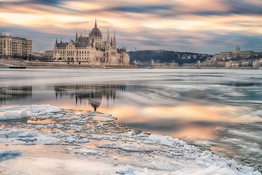 The Hungarian Parliament building at sunset with an icy Danube river