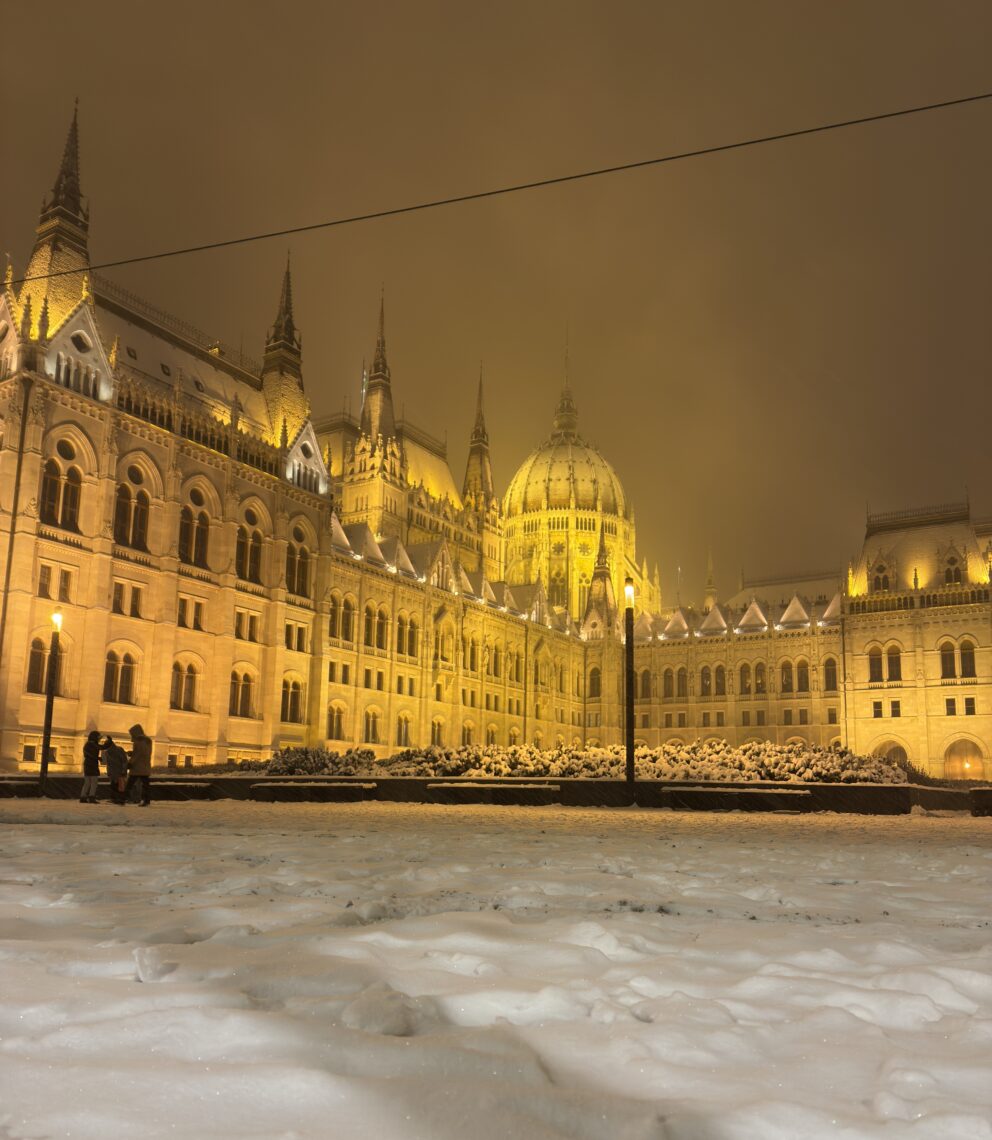The illuminated Hungarian Parliament viewed across a snow-covered Kossuth Square