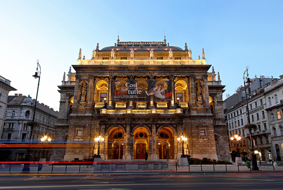 The softly illuminated, grand Neo-Renaissance exterior facade of the Hungarian State Opera House