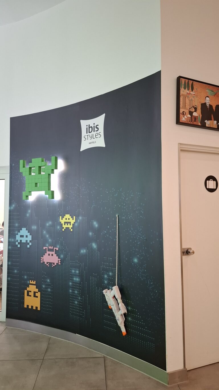 A hotel corridor illuminated heavily by bright neon Tetris-style geometric lights