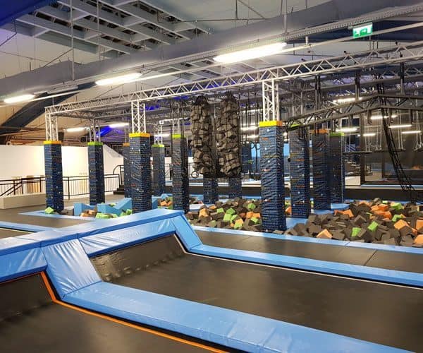 An expansive indoor playground featuring trampolines and jumping obstacle courses