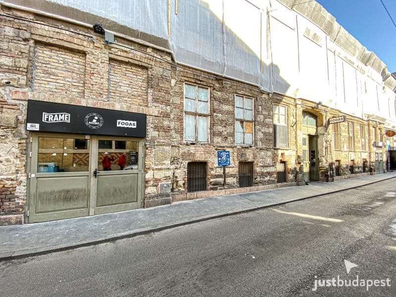 The long, dilapidated brick facade and main entrance of Instant-Fogas on Akácfa utca