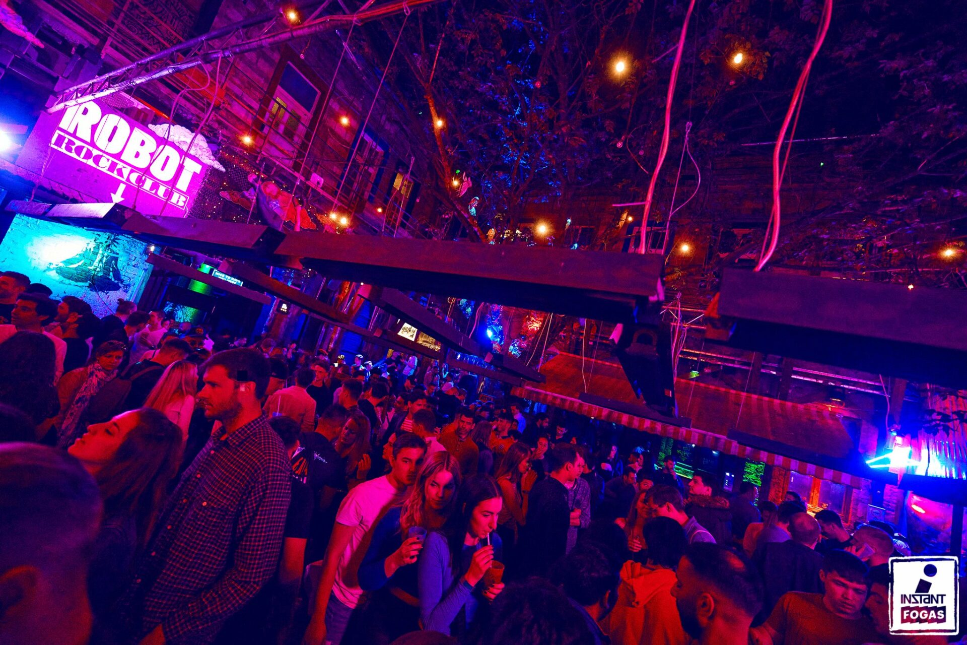 A heavily packed, brightly illuminated central ruin pub courtyard filled with people