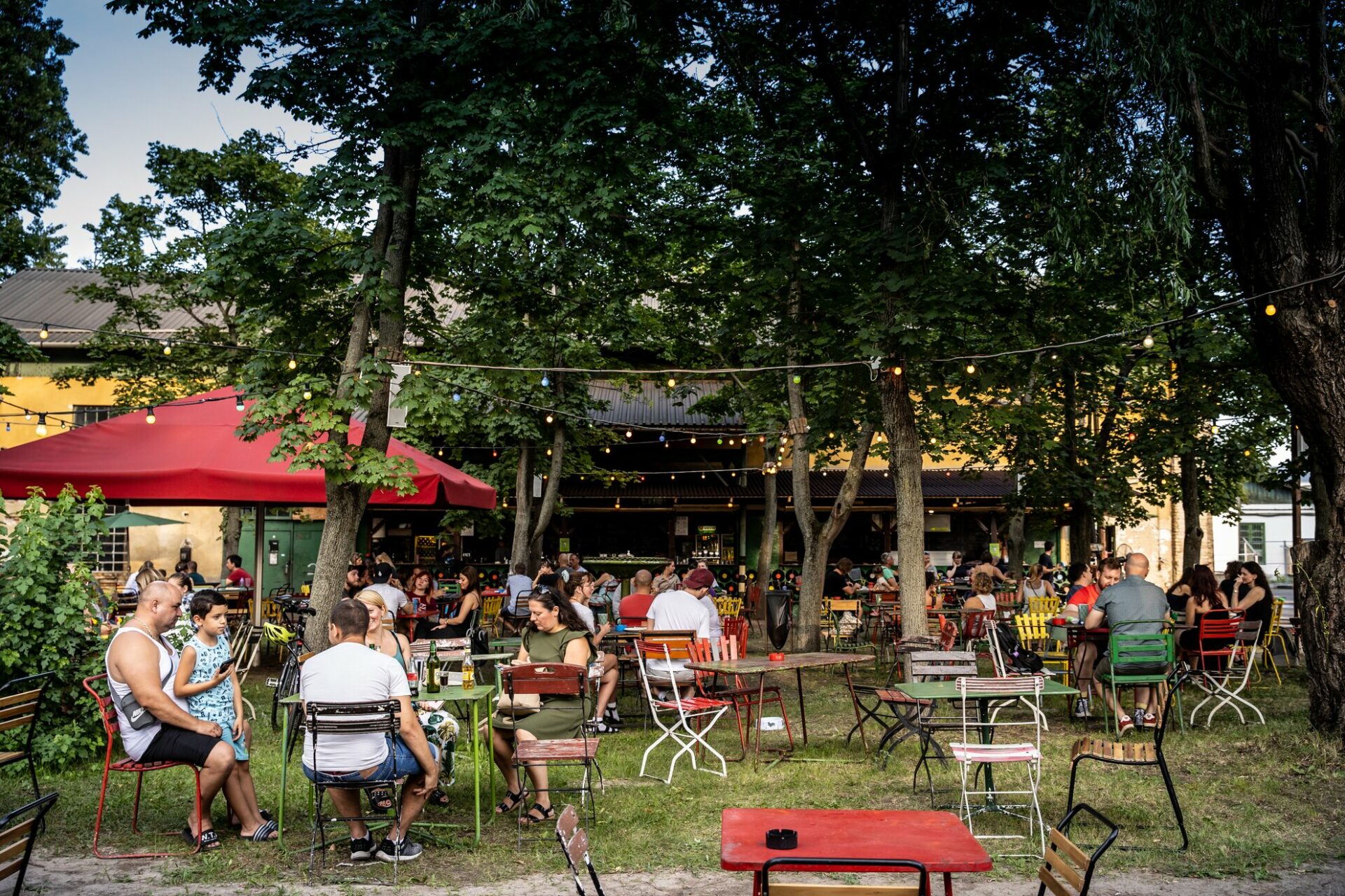 A totally packed outdoor beer garden beautifully illuminated by warm string lights in the trees