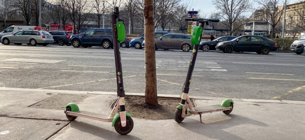A row of green Lime electric scooters parked and ready for rent in central Budapest