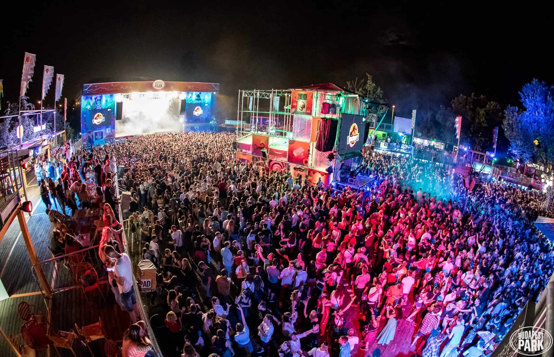 Fans watching a band perform under intense colorful stage lighting in an indoor club