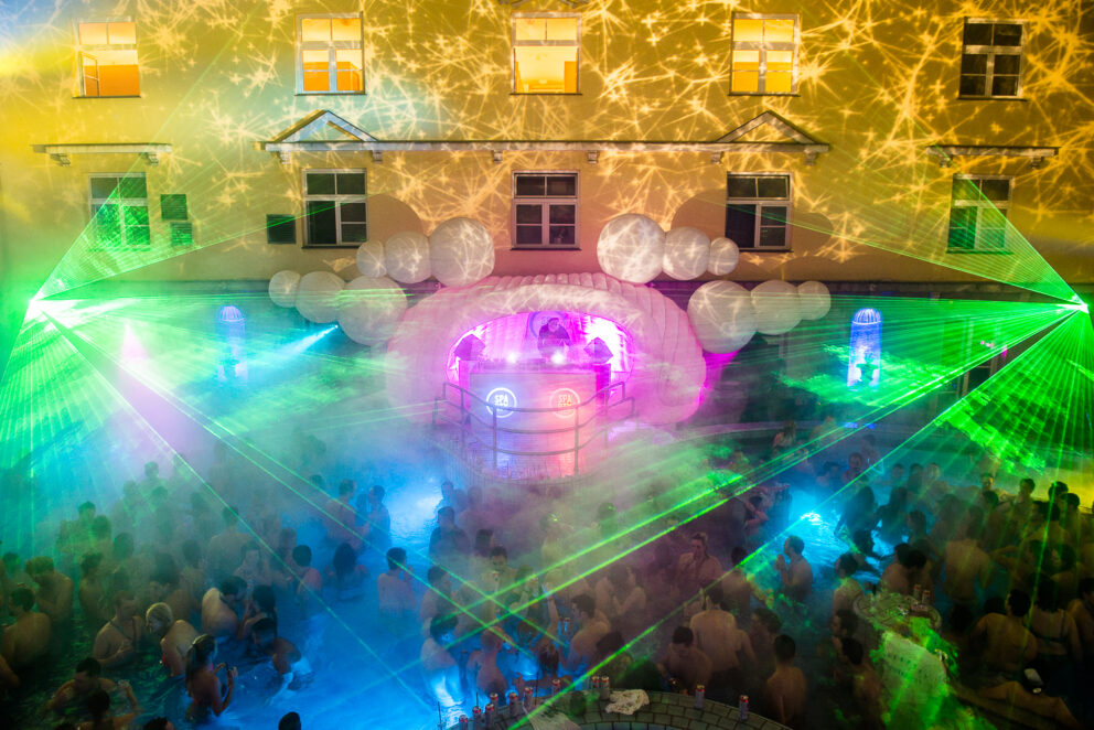 Partygoers enjoying the vibrant atmosphere and light show at the Lukács Baths in Budapest
