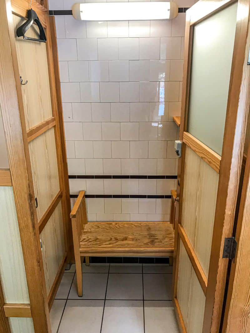 A precisely uniform row of painted wooden private changing cabanas safely inside the vintage locker room