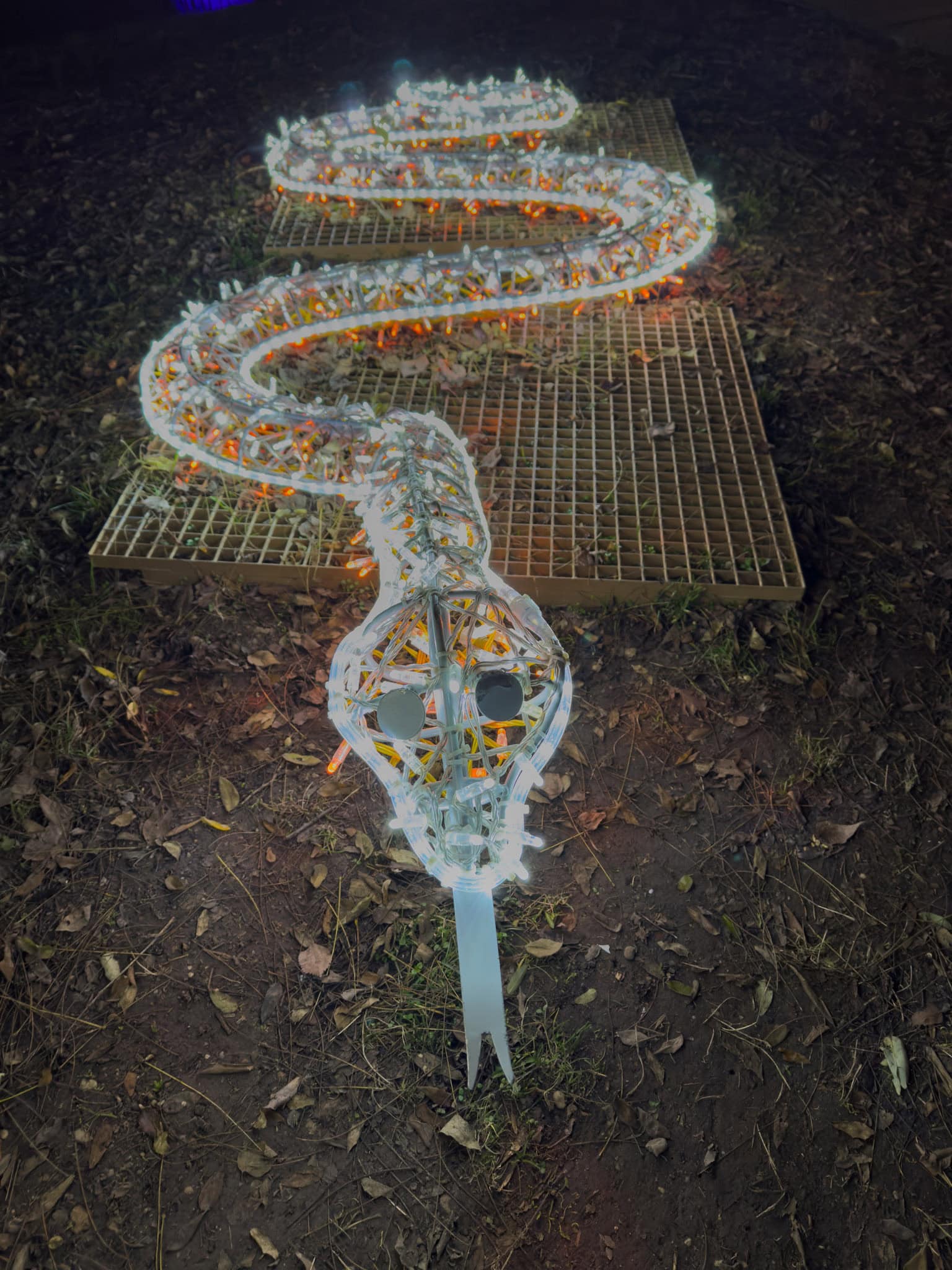 A giant brightly colored snake coiled tightly around a real tree trunk