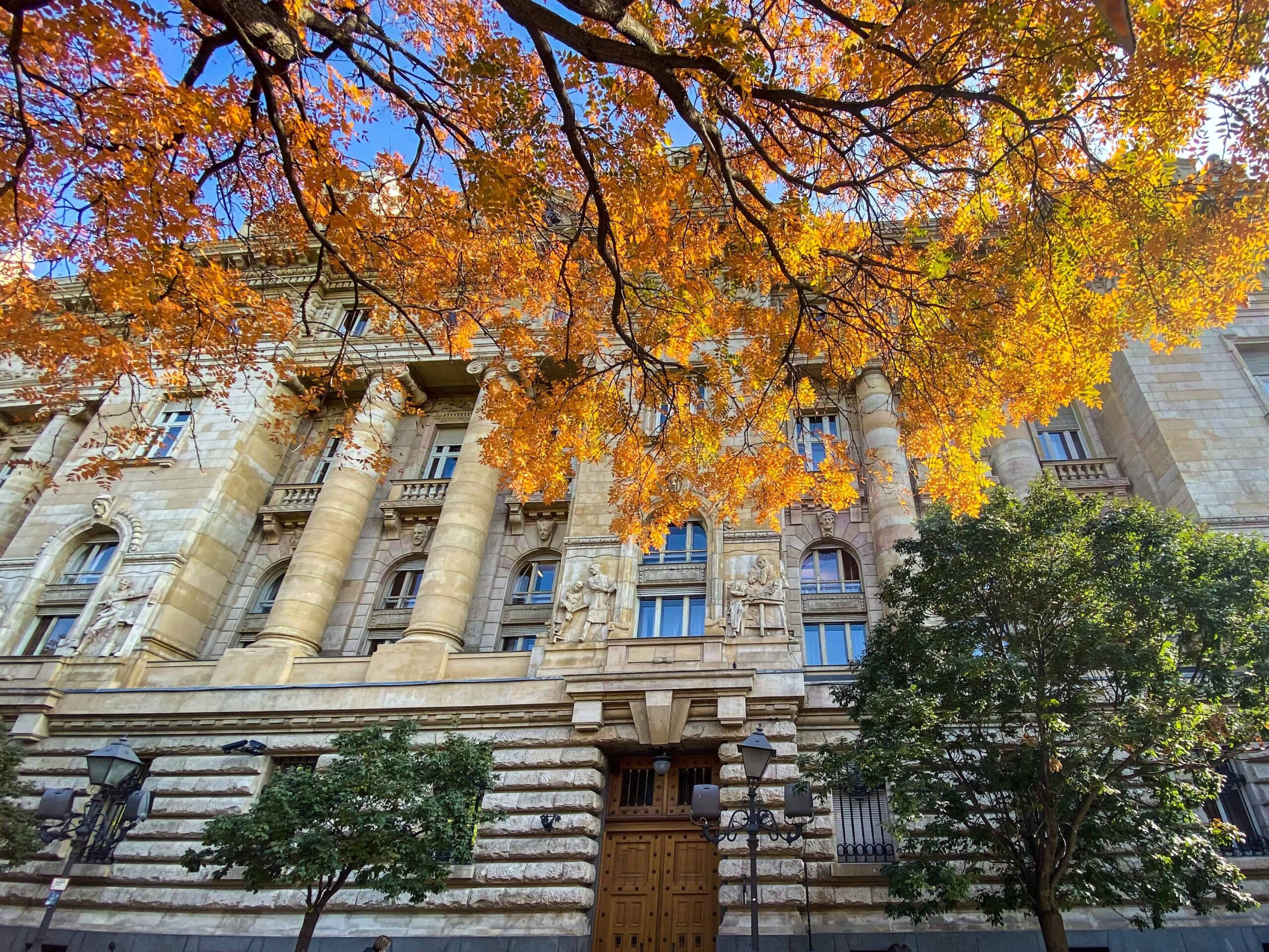The grand classical facade of the Hungarian National Bank viewed through autumn leaves
