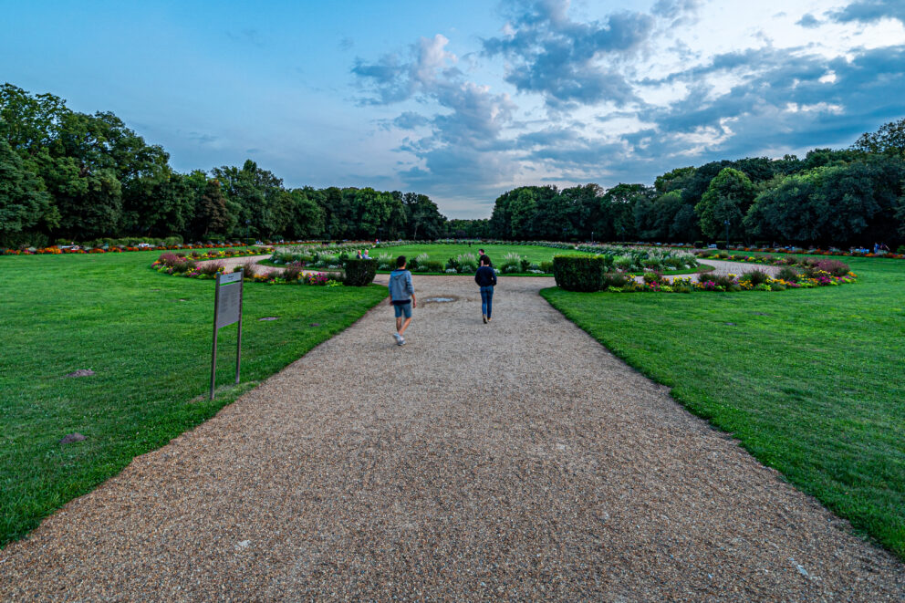 A gravel pathway leading to a circular flower garden in the green park of Margaret Island