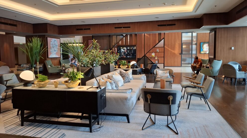 A wide daytime shot clearly showcasing the massive stepped modern hotel building situated right on the riverbank