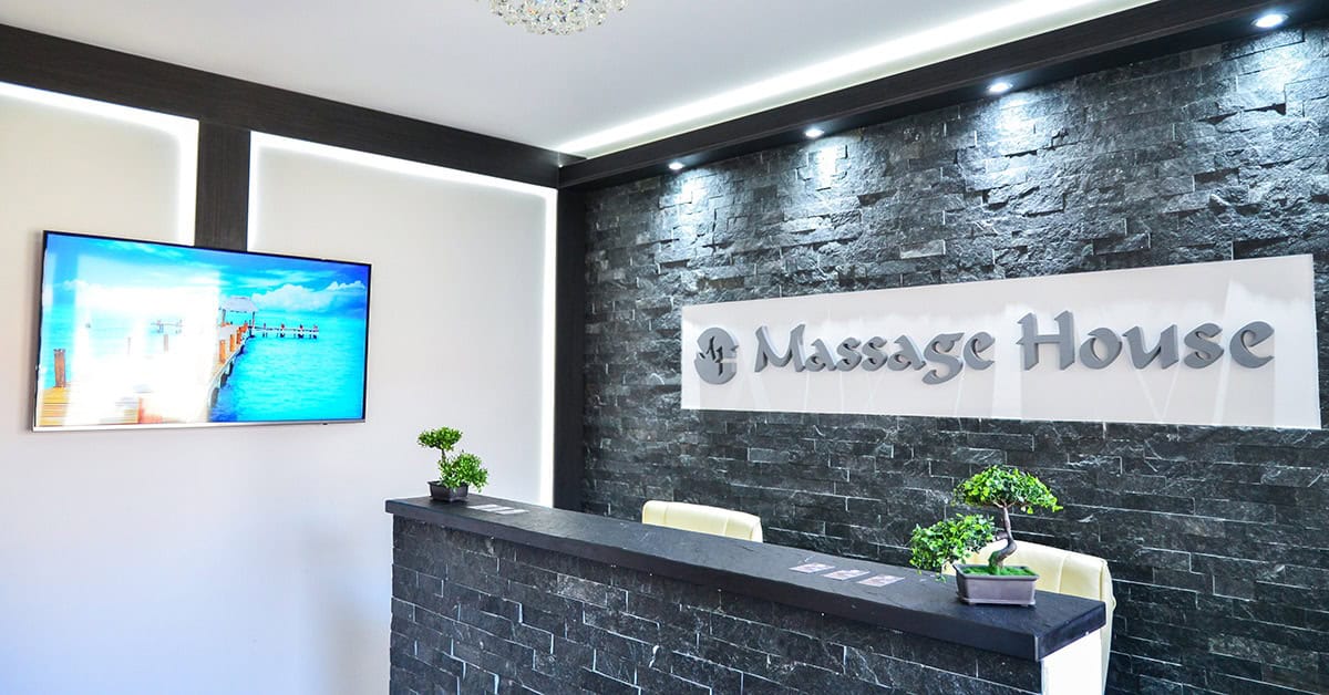 A clean modern interior an professional dark stone reception desk displaying the Massage House logo