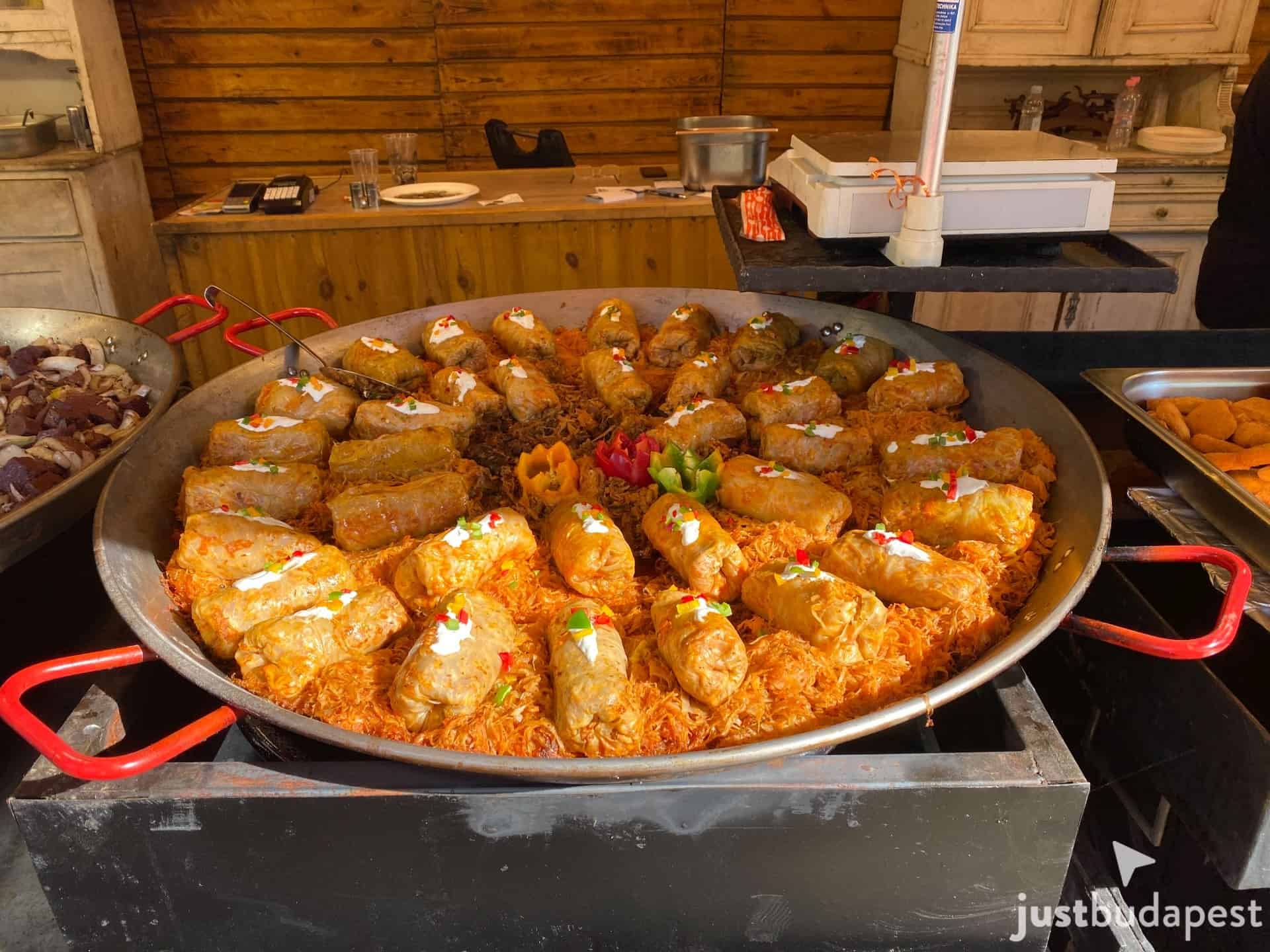 Dozens of stuffed cabbage rolls cooking in a giant pan at an outdoor market