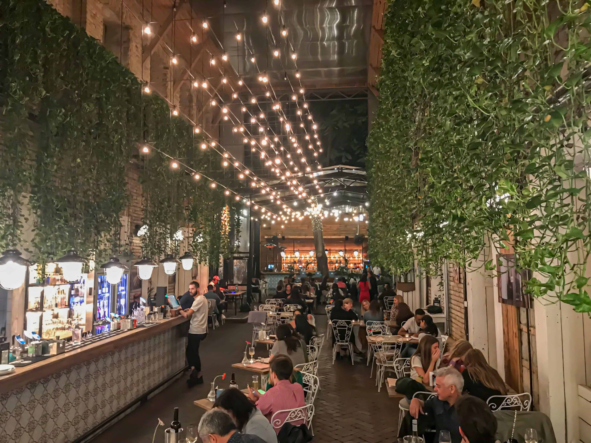 Diners enjoying their meals comfortably seated in the brightly lit brick courtyard under the glass roof
