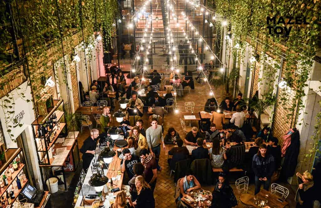 The lush, heavily decorated indoor courtyard dining area of Mazel Tov
