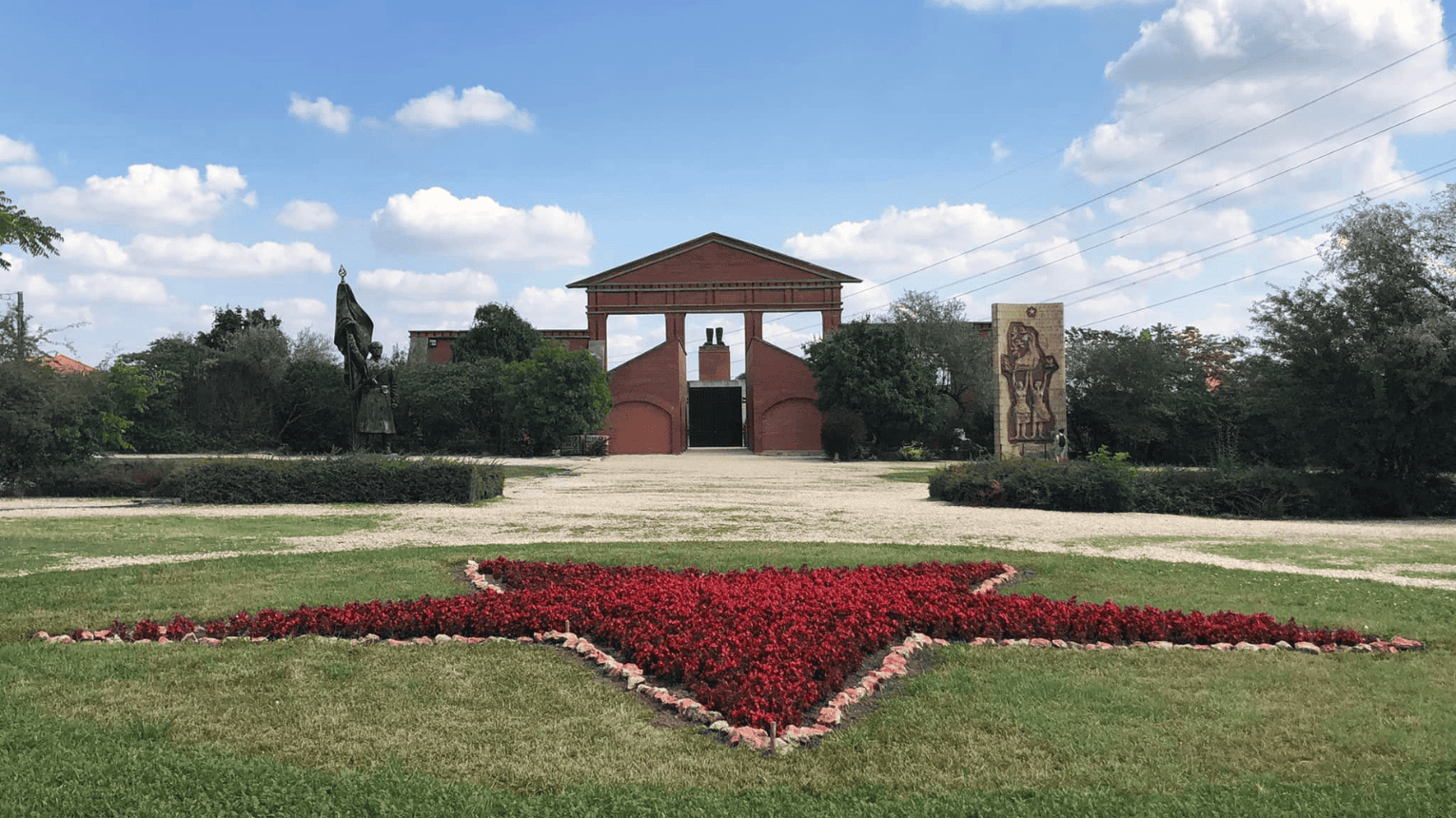 The brick entrance of Memento Park in Budapest with a red flower star in the foreground