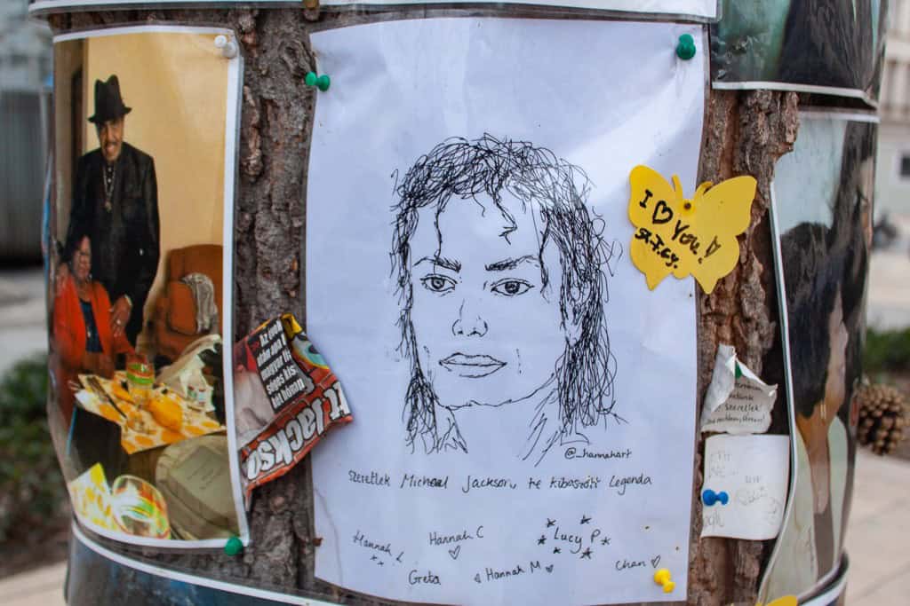 The Michael Jackson Memorial Tree closely decorated with fan-made sketches, flowers, and printed photographs