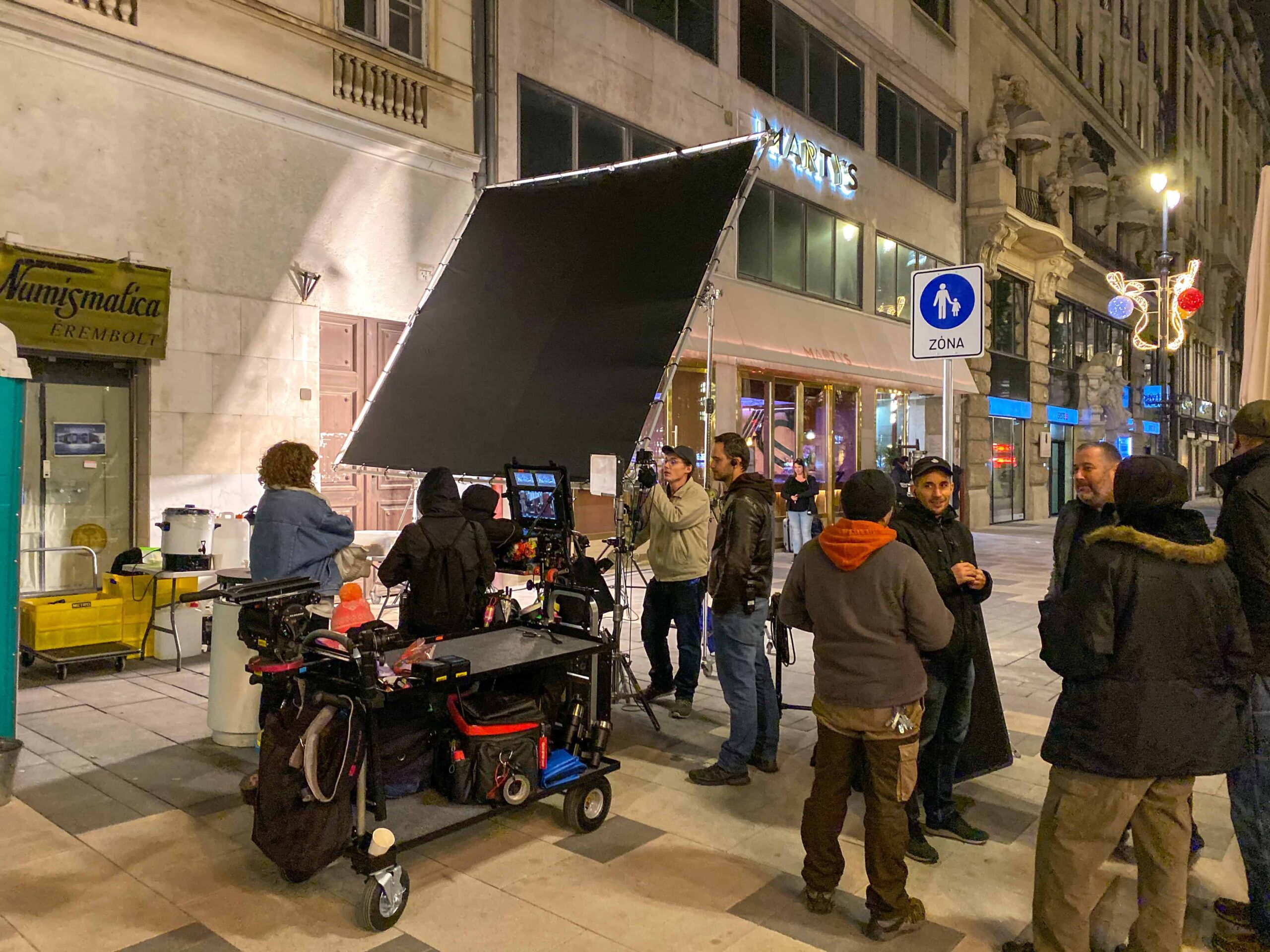 A professional cinema clapperboard in focus positioned in front of the historical architecture of Budapest