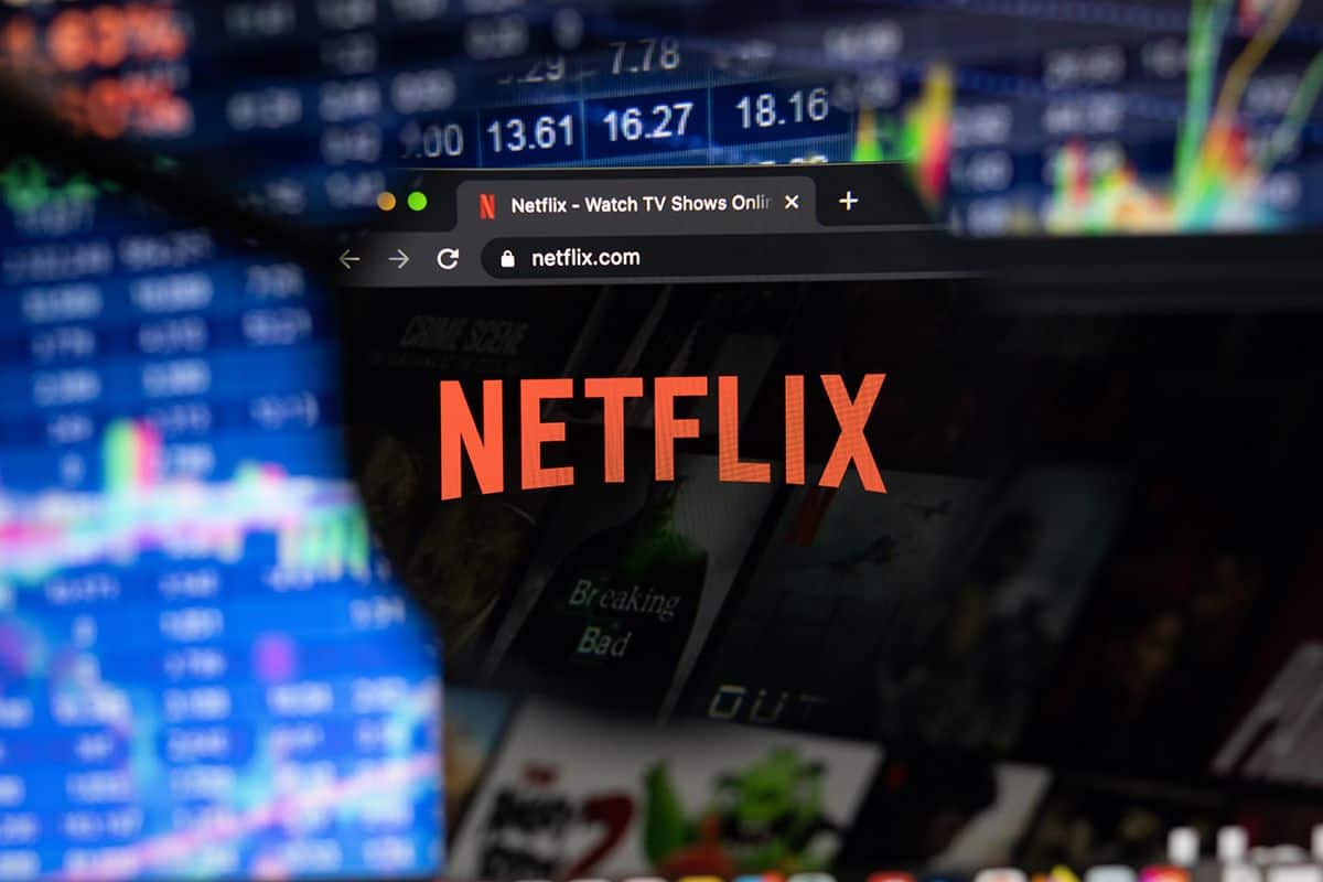 A digital web browser displaying the red Netflix logo with blurry stock market data in the foreground