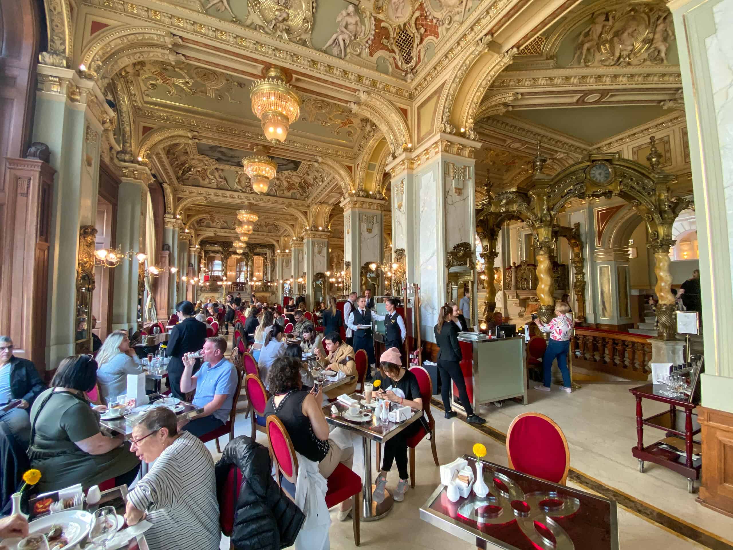 A busy bustling interior showing tourists seated down the main gallery hall with waitstaff in formal uniforms