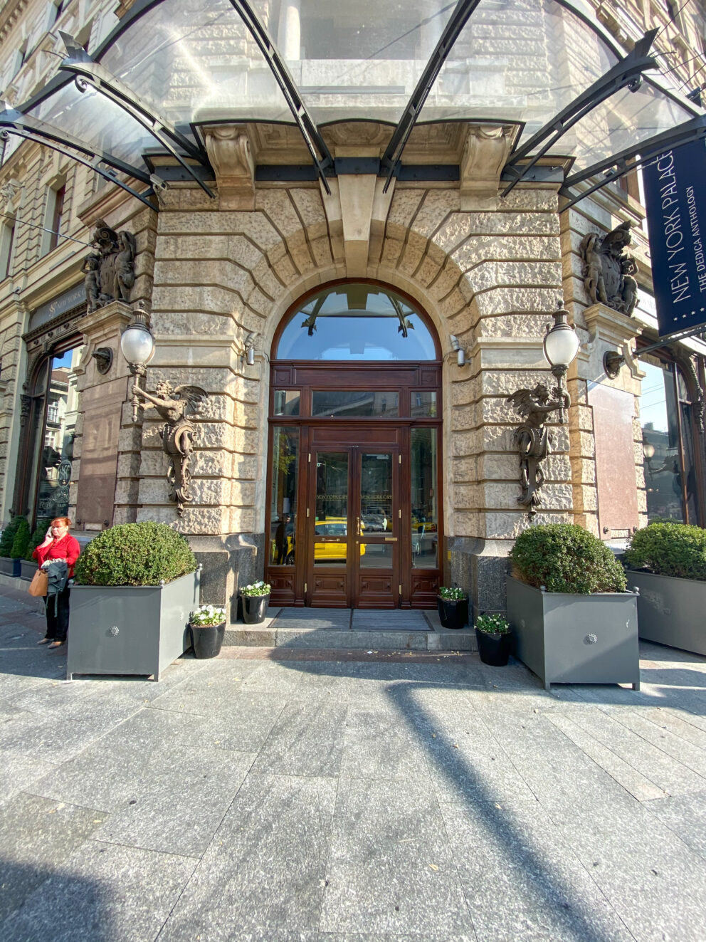 The heavy ornate arched wooden main entrance doors to the New York Palace venue guarded by carved stone angels