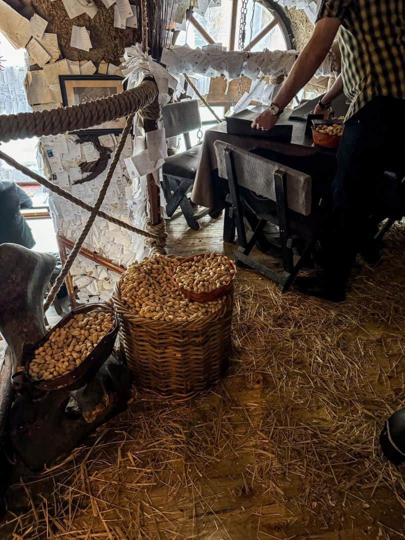 The floor beneath a wooden dining table completely covered in discarded peanut shells