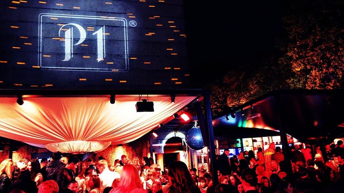 A crowded outdoor late-night club scene explicitly showing hundreds of densely packed partygoers dancing