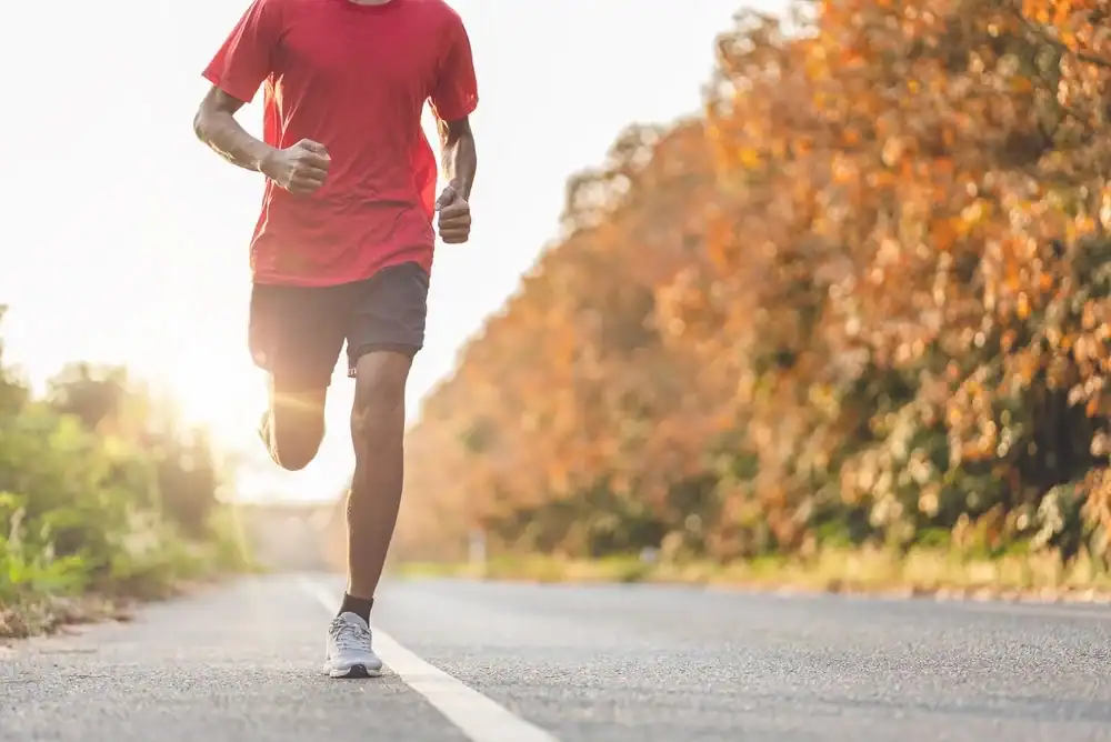 A man enjoying an autumn run on a paved park path in Budapest