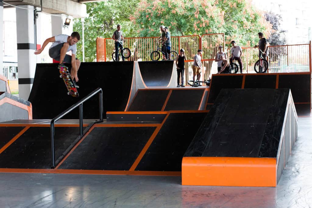 A skateboarder performing a trick at an outdoor skate and BMX park in Budapest