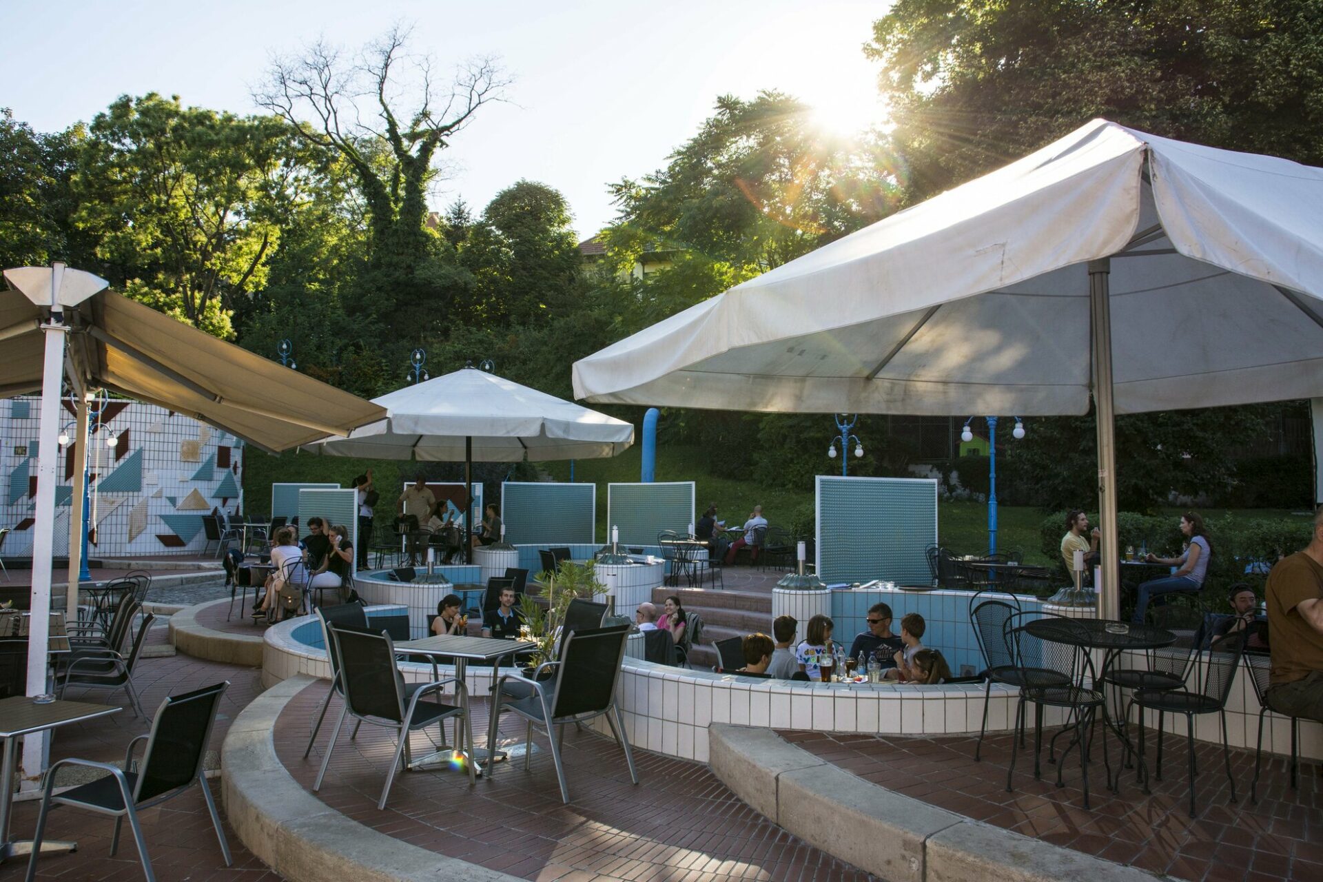People drinking at tables set up playfully inside drained tiled swimming pools