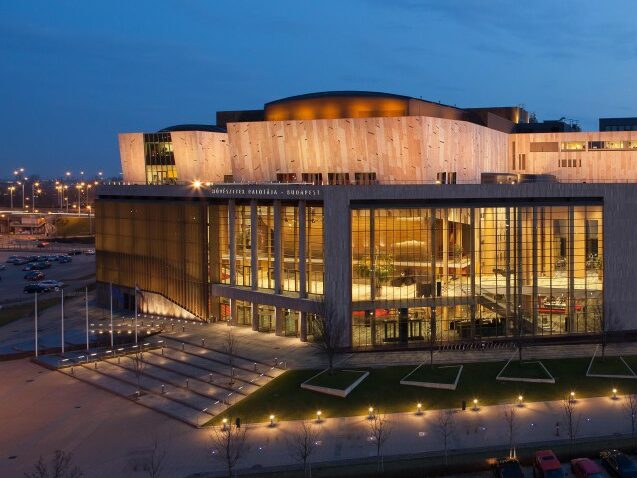 A full symphony orchestra performing inside the expansive National Concert Hall at Müpa