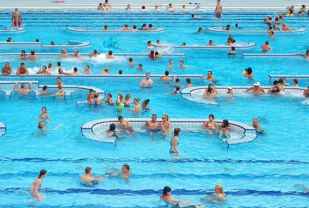 People relaxing in an outdoor thermal pool with submerged white tiled seating