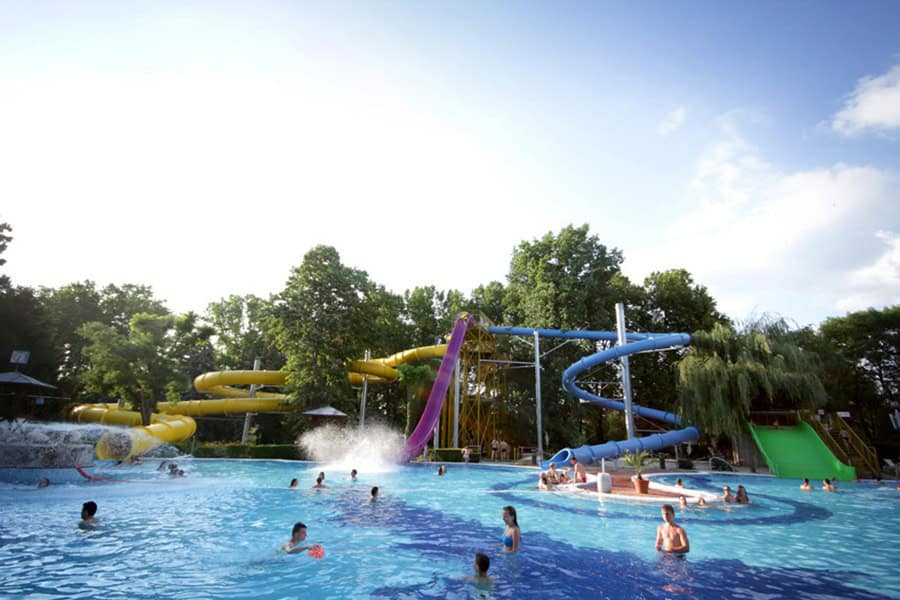 A large outdoor pool with yellow and purple tube slides