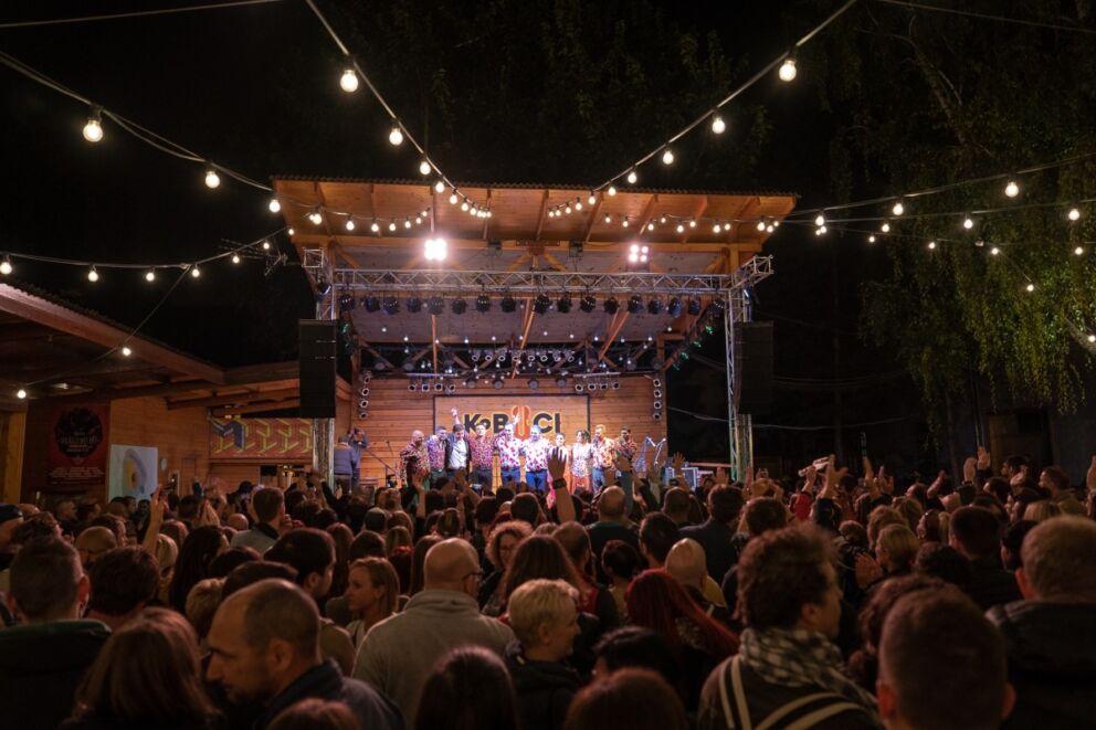Thousands of fans holding up glowing phones at a massive indoor concert inside the Papp László Sportaréna
