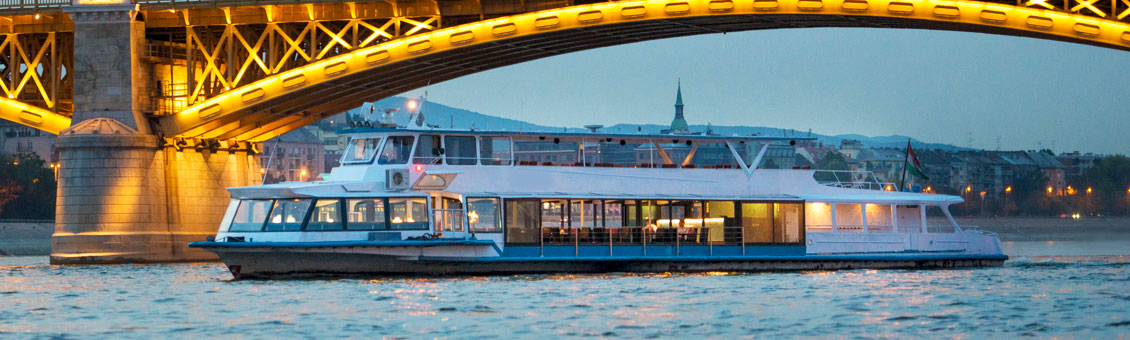 A massive crowd dancing under laser lights on the rooftop deck of a Danube party boat