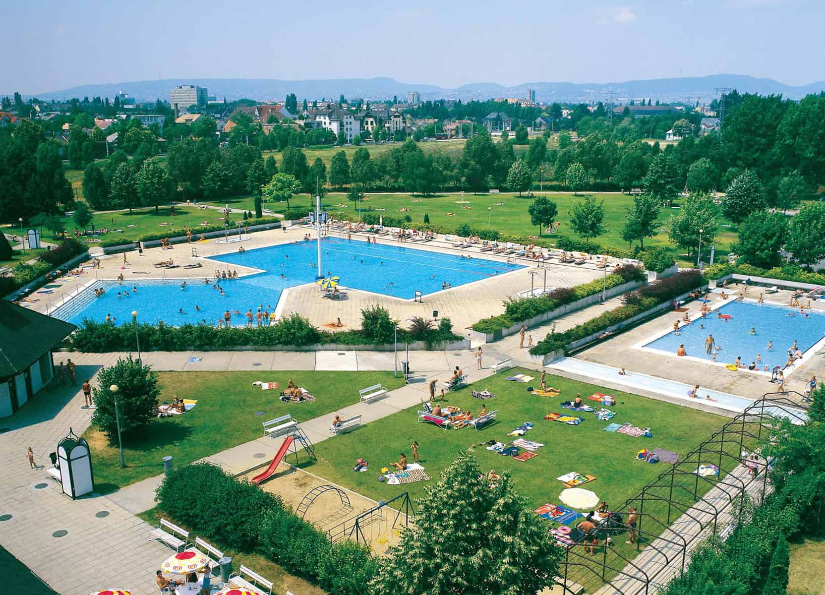 An aerial view of the expansive outdoor pools and green lawns at Paskal Baths