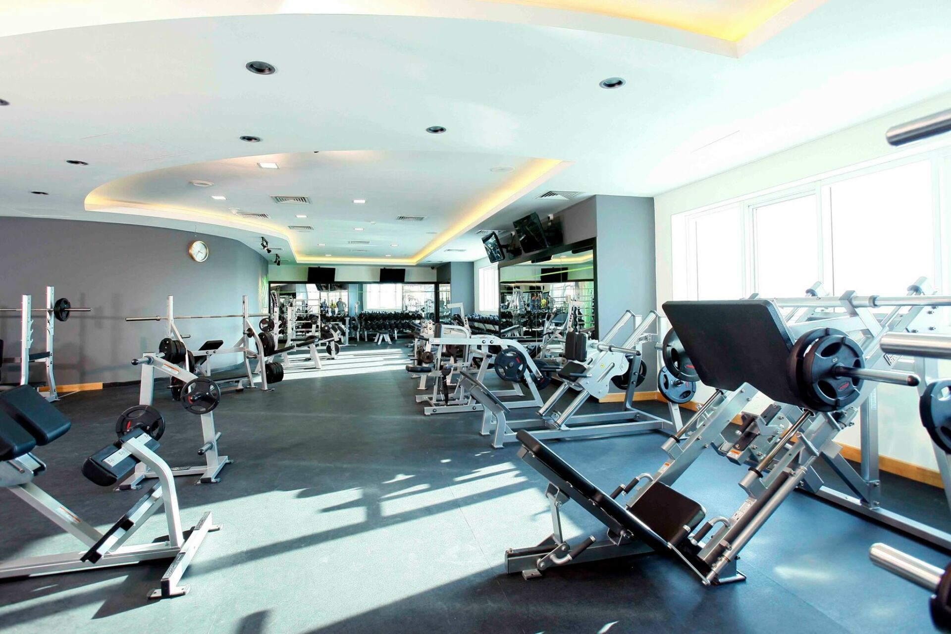 A muscular man lifting heavy dumbbells on a bench in a modern gym