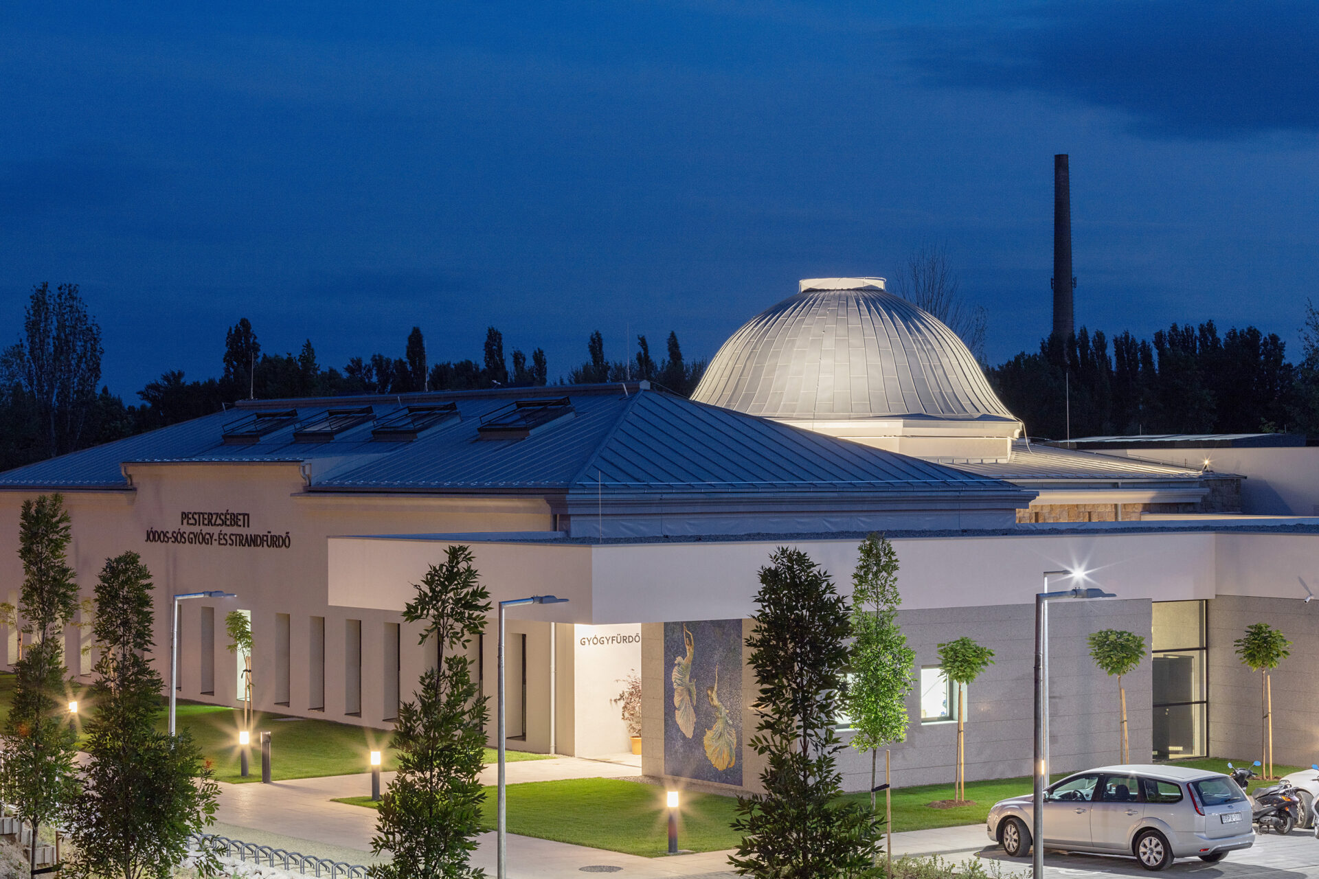 The illuminated historic dome and modern exterior of Pesterzsebet Bath at night